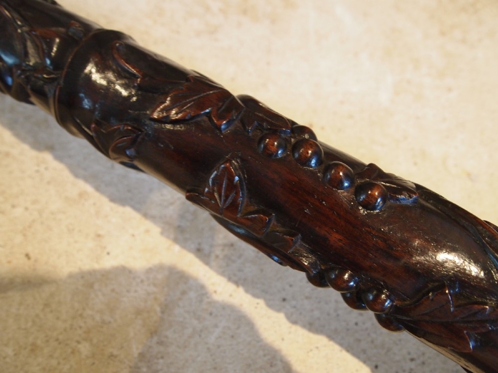A tall early 20th-century Burmese standard lamp crafted from dark padouk wood, featuring intricate high-relief carving along the entire column and base. View V
