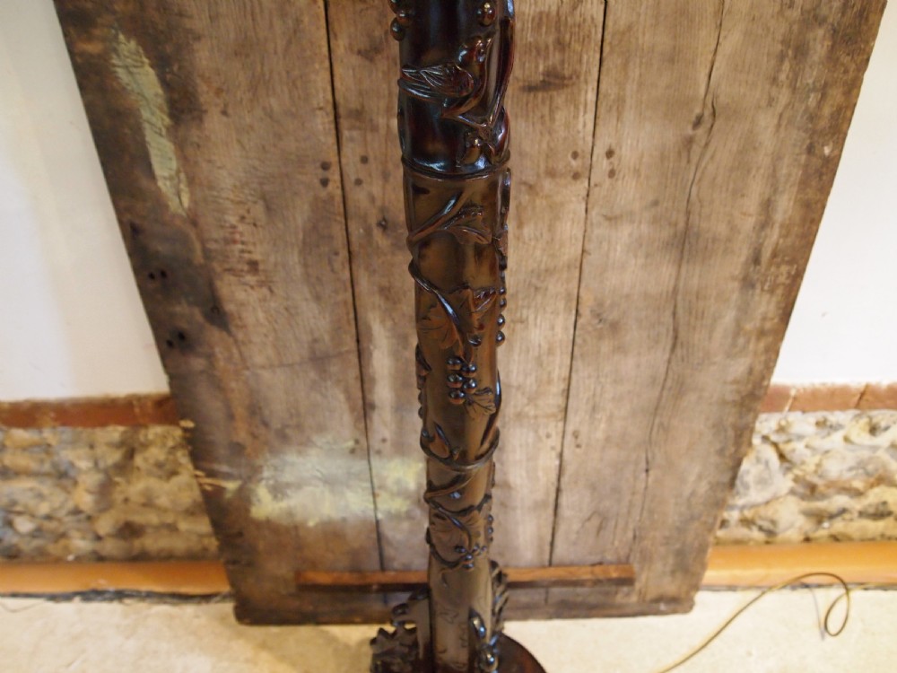 A tall early 20th-century Burmese standard lamp crafted from dark padouk wood, featuring intricate high-relief carving along the entire column and base. View VIII
