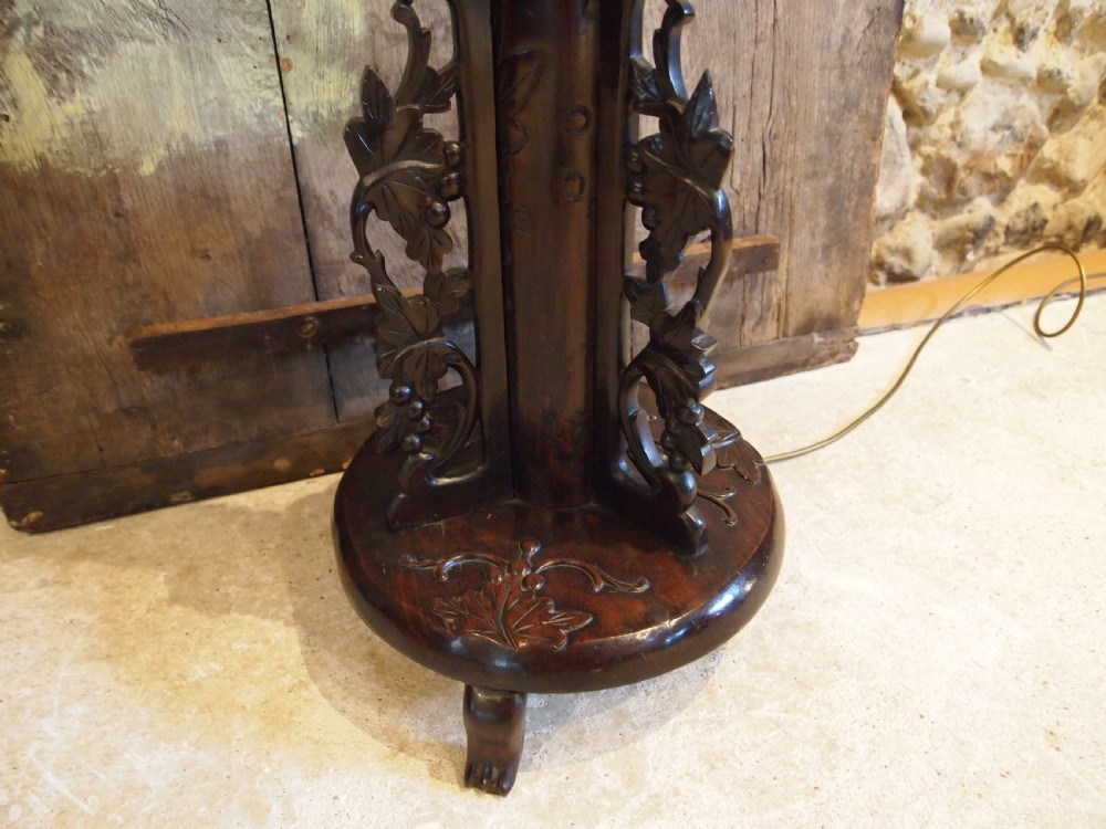 A tall early 20th-century Burmese standard lamp crafted from dark padouk wood, featuring intricate high-relief carving along the entire column and base. View IX