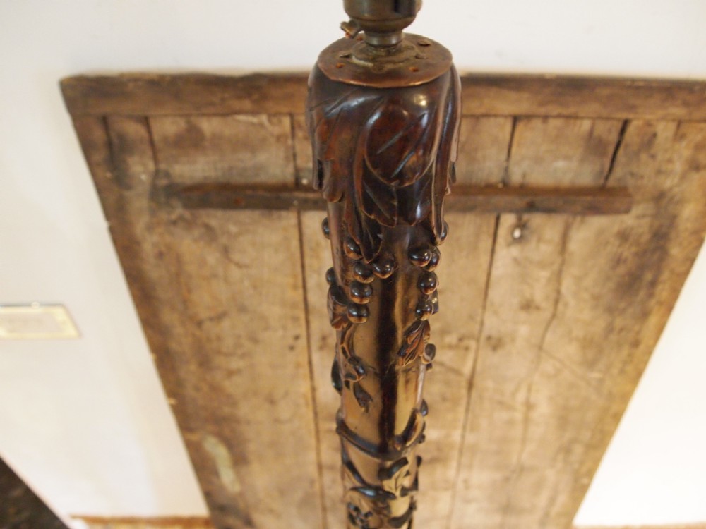 A tall early 20th-century Burmese standard lamp crafted from dark padouk wood, featuring intricate high-relief carving along the entire column and base. View XI