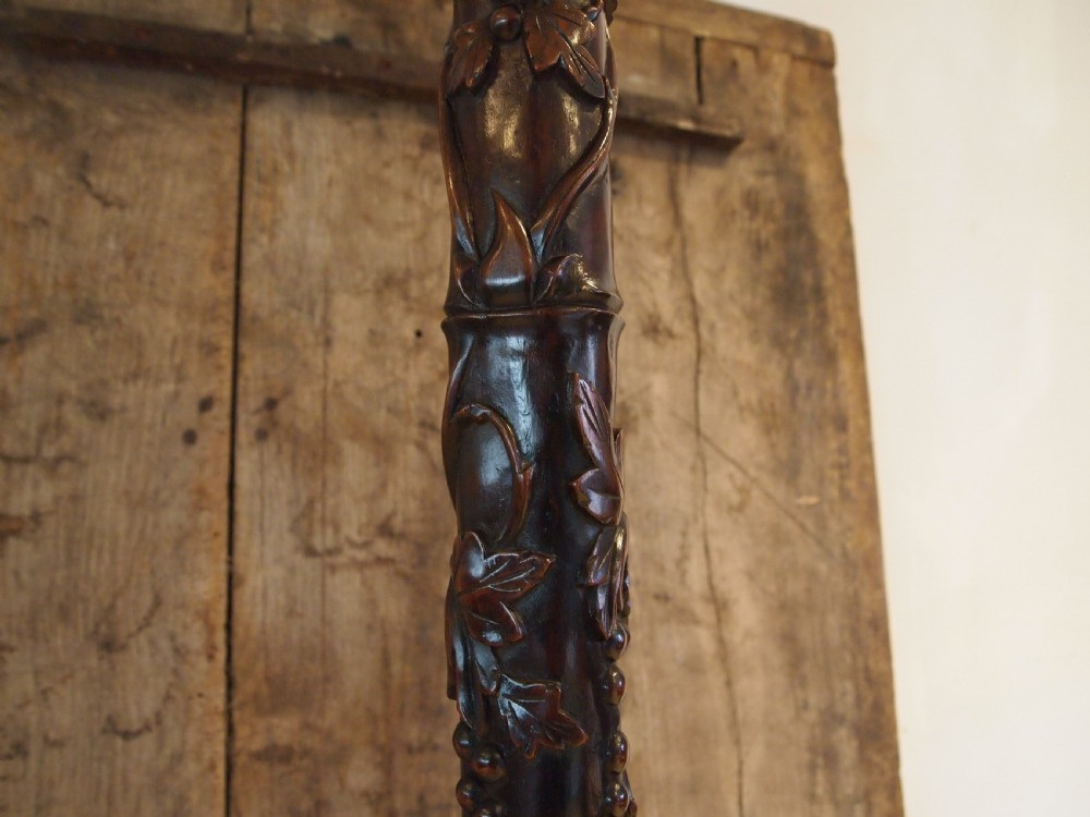 A tall early 20th-century Burmese standard lamp crafted from dark padouk wood, featuring intricate high-relief carving along the entire column and base. View XII