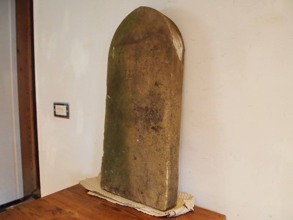A weathered Victorian York stone headstone with an arched top, featuring carved initials and the date 1868. View III