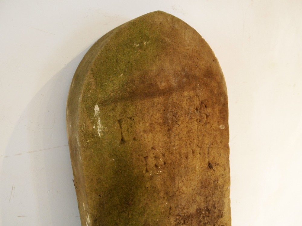 A weathered Victorian York stone headstone with an arched top, featuring carved initials and the date 1868. View IV