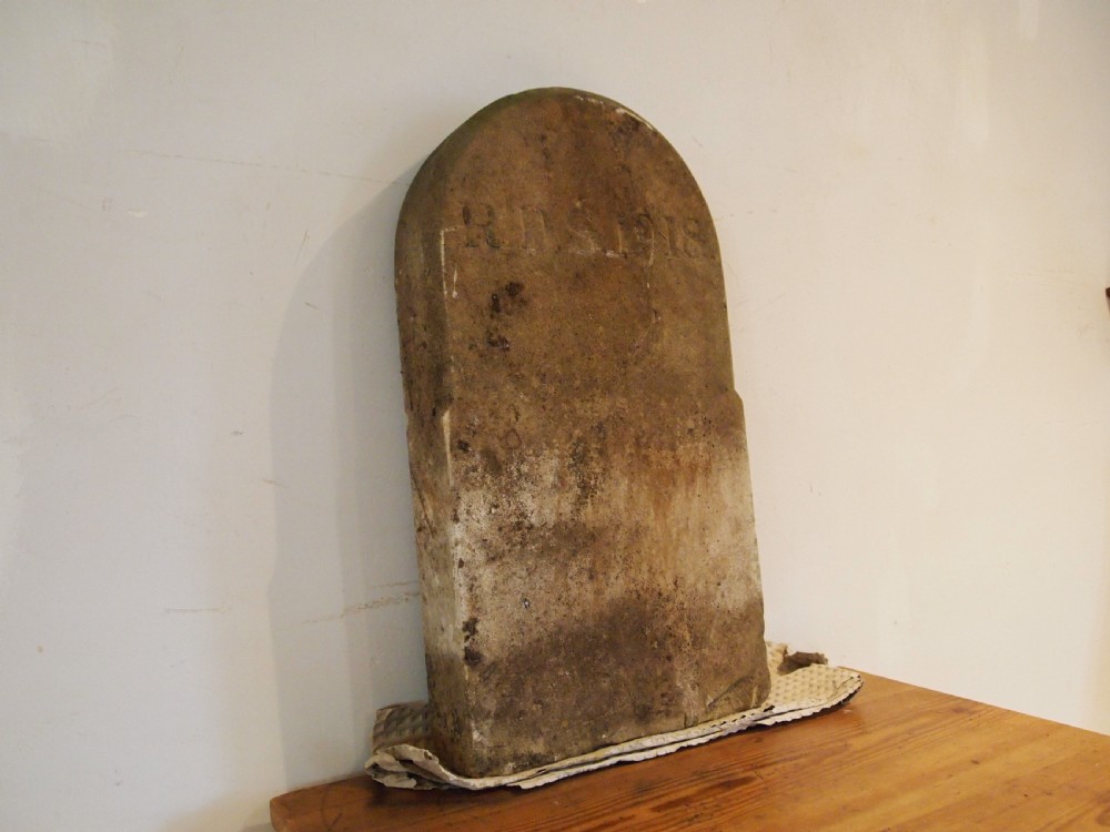 A weathered Victorian York stone headstone with an arched top, featuring carved initials and the date 1868. View VI