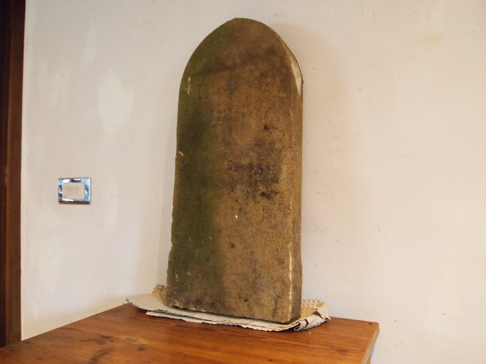 A weathered Victorian York stone headstone with an arched top, featuring carved initials and the date 1868. View VIII