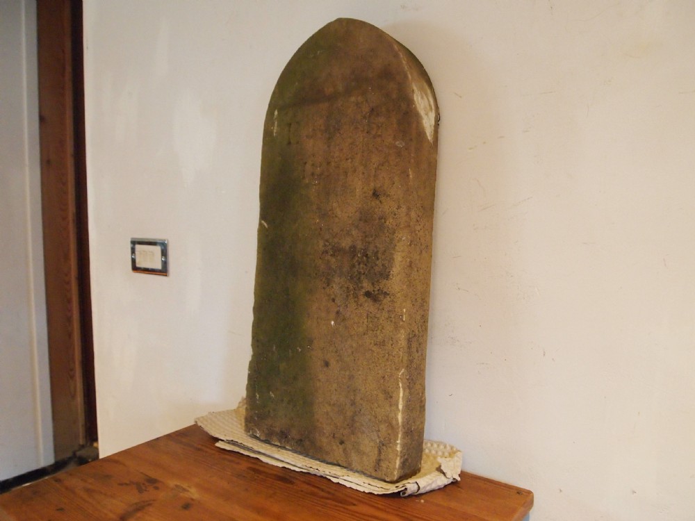 A weathered Victorian York stone headstone with an arched top, featuring carved initials and the date 1868. View IX