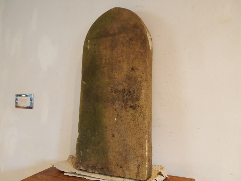 A weathered Victorian York stone headstone with an arched top, featuring carved initials and the date 1868. View X