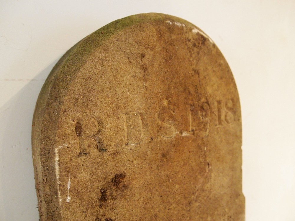 An arched top York stone headstone dated 1918 with hand-carved initials and weathered buff surface. View VI
