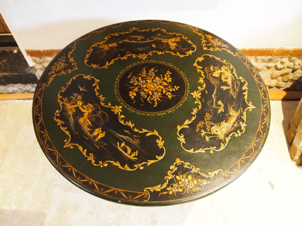A circular black lacquered tilt-top table featuring intricate gold gilt Chinoiserie cartouches resting on a tripod pedestal base. View III