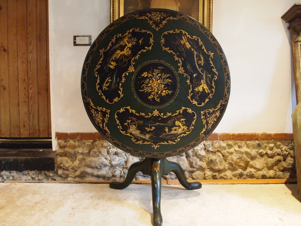 A circular black lacquered tilt-top table featuring intricate gold gilt Chinoiserie cartouches resting on a tripod pedestal base. View IX