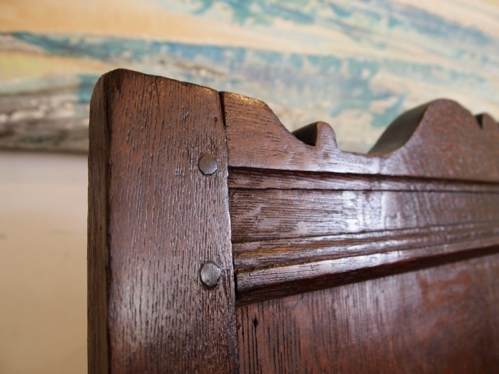 An early 18th-century dark oak lambing chair featuring a high panelled back, enclosed box base, integrated shaped arms, and a cut crest rail. View VI