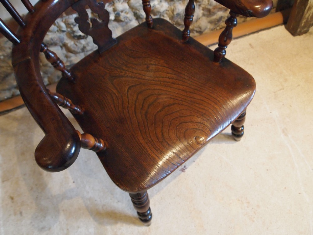 An antique 19th-century yew wood Windsor armchair featuring a bowed top rail, pierced central splat, turned spindles, armrests, and turned legs joined by an H-stretcher. View II