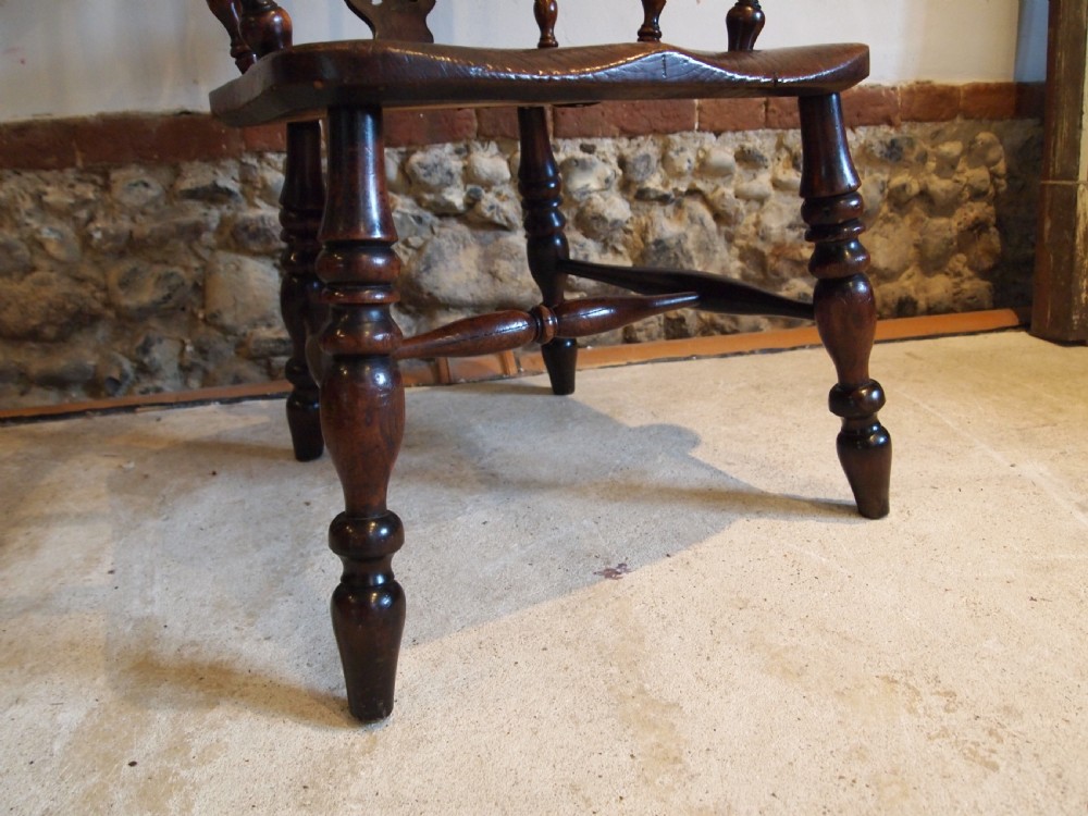 An antique 19th-century yew wood Windsor armchair featuring a bowed top rail, pierced central splat, turned spindles, armrests, and turned legs joined by an H-stretcher. View IX