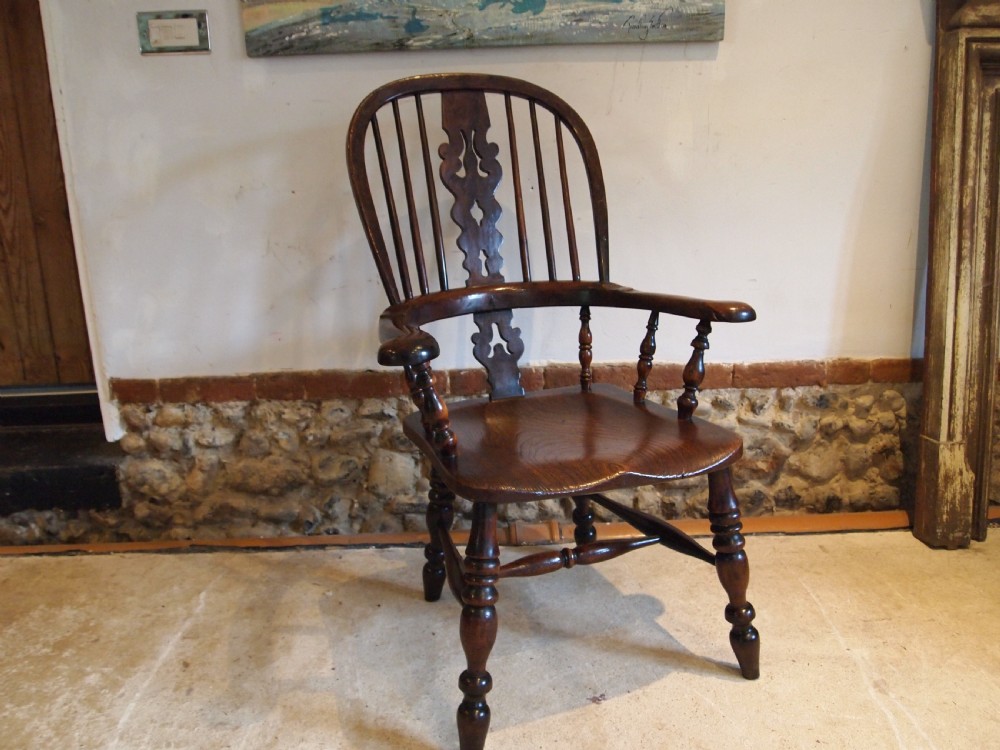 An antique 19th-century yew wood Windsor armchair featuring a bowed top rail, pierced central splat, turned spindles, armrests, and turned legs joined by an H-stretcher. View XII