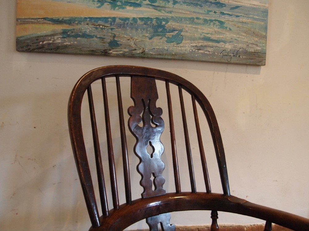 An antique 19th-century yew wood Windsor armchair featuring a bowed top rail, pierced central splat, turned spindles, armrests, and turned legs joined by an H-stretcher. View XIII