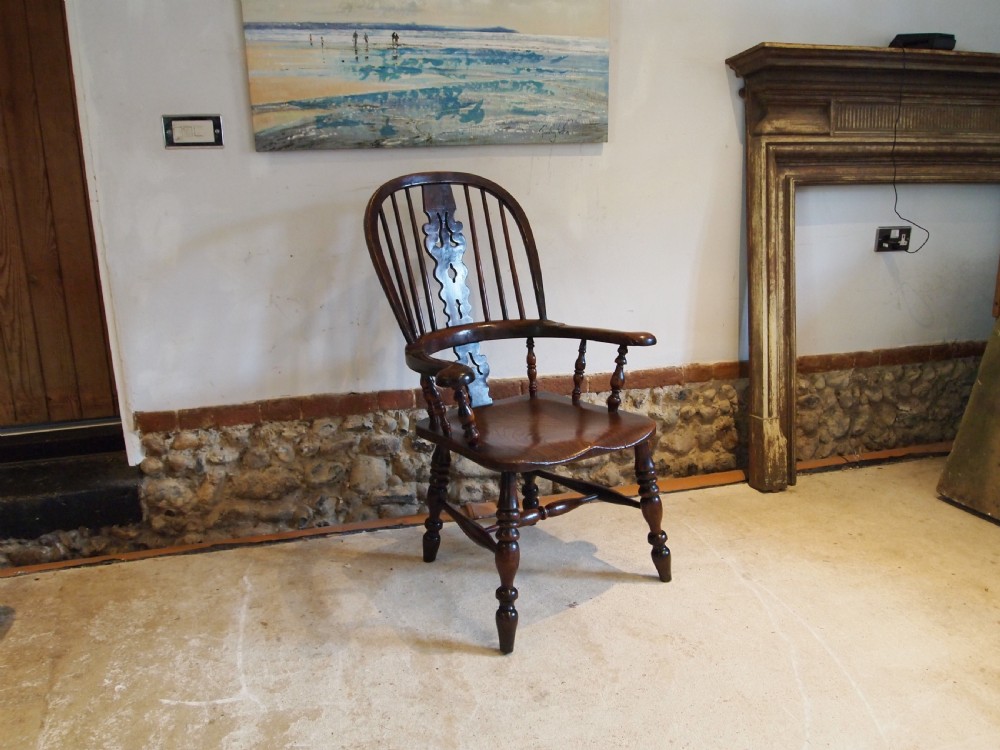 An antique 19th-century yew wood Windsor armchair featuring a bowed top rail, pierced central splat, turned spindles, armrests, and turned legs joined by an H-stretcher. View XIV