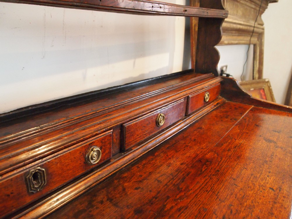 An 18th-century Welsh oak potboard dresser featuring an open plate rack, small upper drawers, a base with main drawers, shaped aprons, and turned legs. View VI