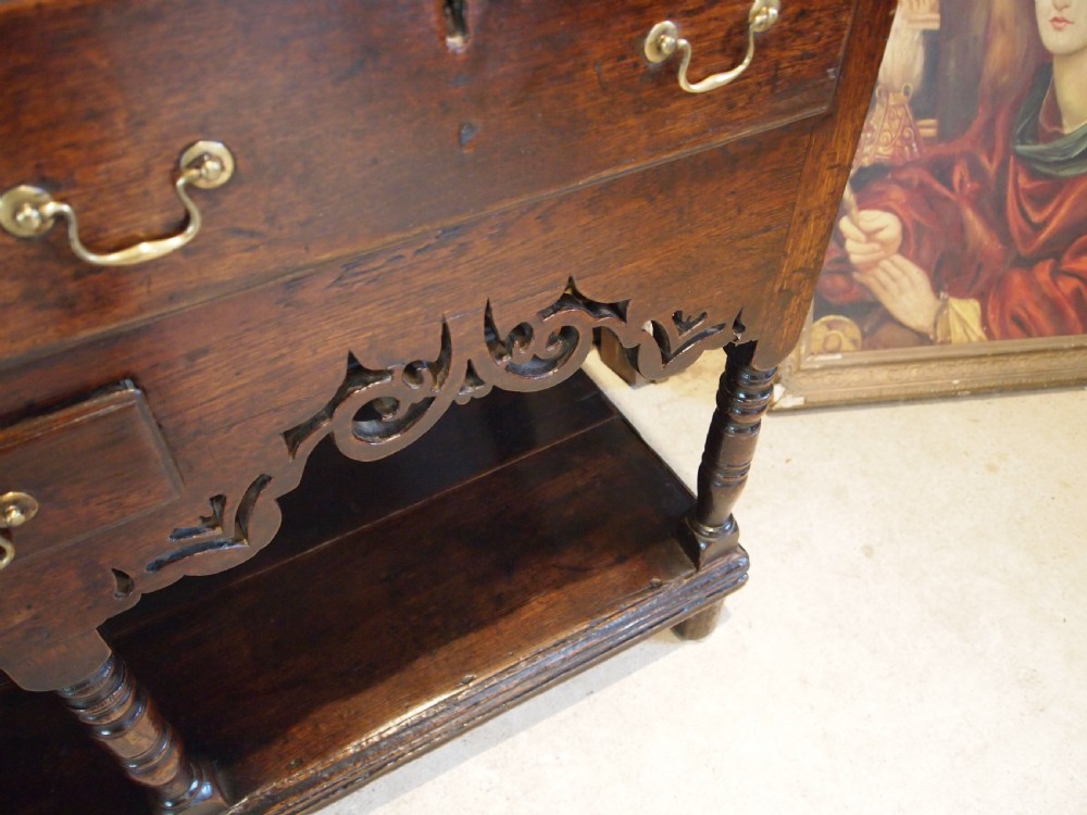 An 18th-century Welsh oak potboard dresser featuring an open plate rack, small upper drawers, a base with main drawers, shaped aprons, and turned legs. View XIV