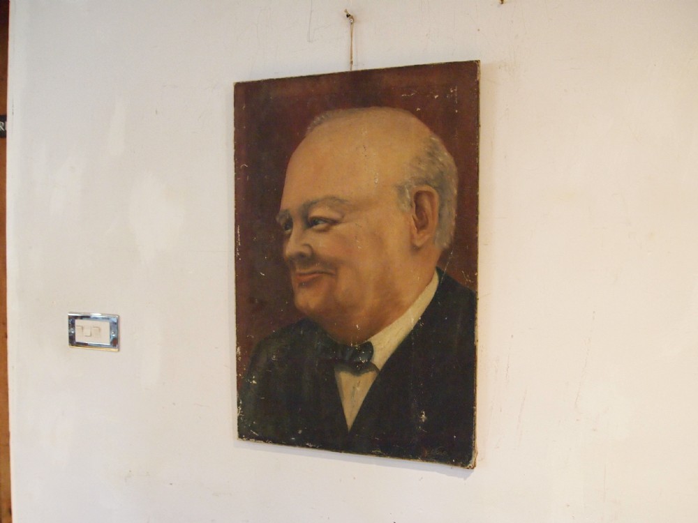 An unframed oil painting on canvas depicting a portrait of Sir Winston Churchill in profile against a dark brown background.