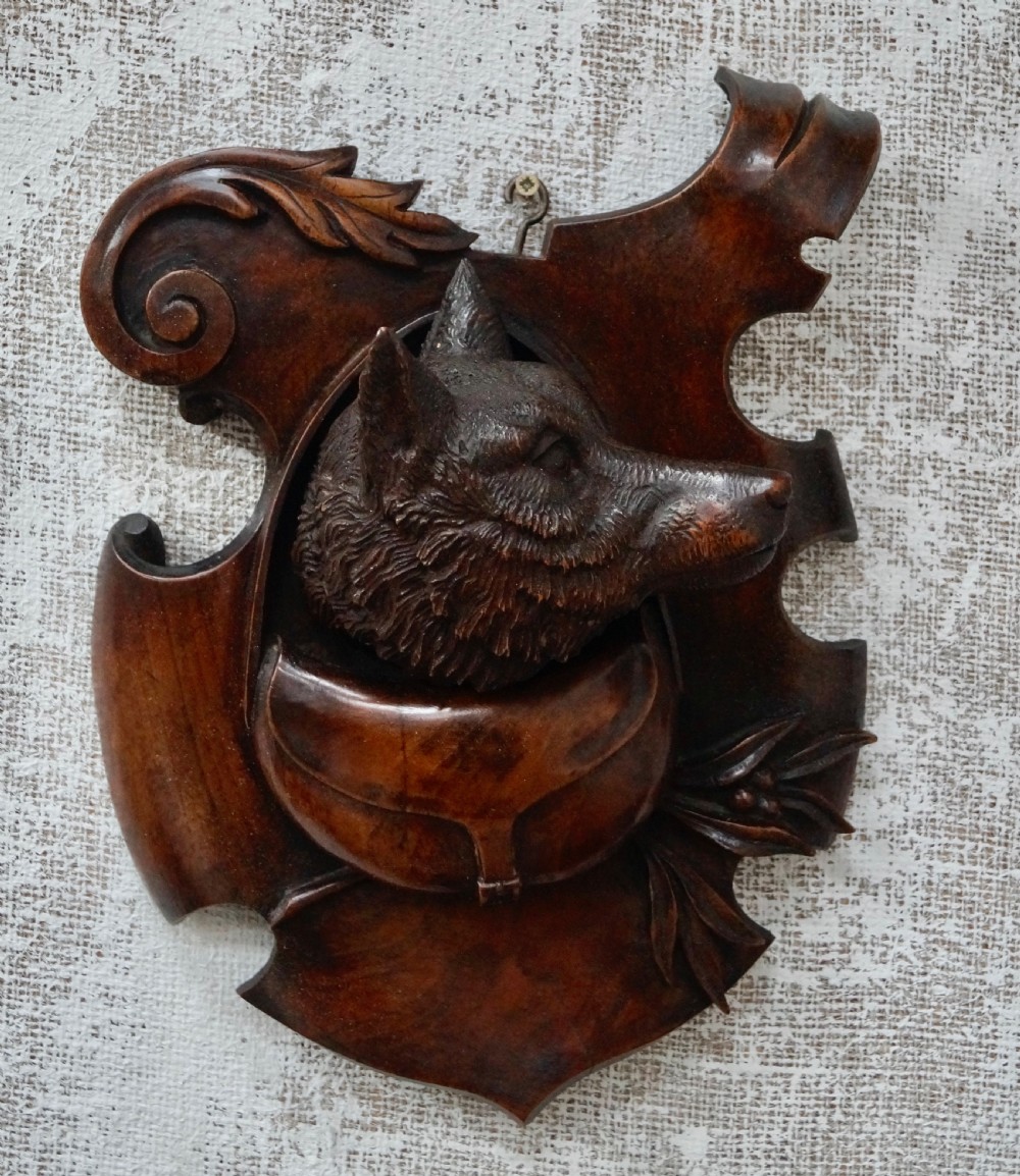 A pair of dark carved wooden shield-shaped wall plaques depicting relief heads of a fox and a hunting hound alongside sporting accessories. View II