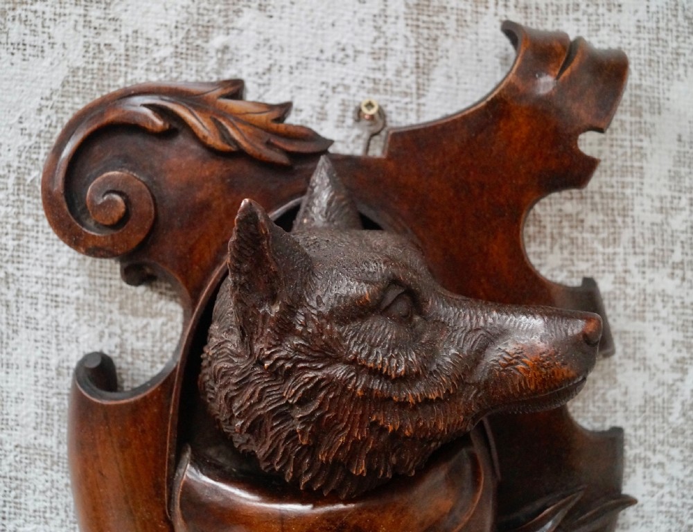 A pair of dark carved wooden shield-shaped wall plaques depicting relief heads of a fox and a hunting hound alongside sporting accessories. View III
