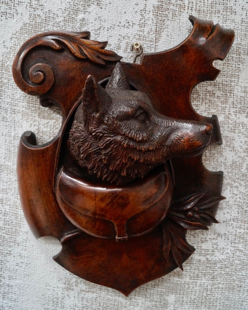 A pair of dark carved wooden shield-shaped wall plaques depicting relief heads of a fox and a hunting hound alongside sporting accessories. View IV