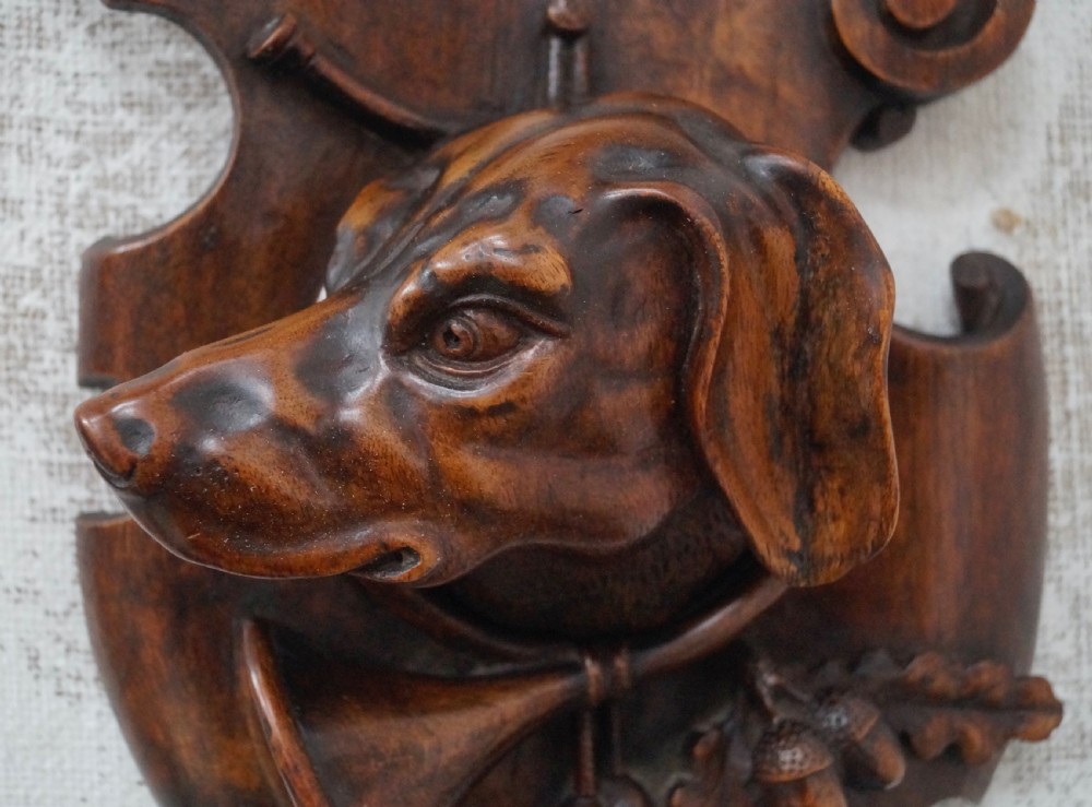 A pair of dark carved wooden shield-shaped wall plaques depicting relief heads of a fox and a hunting hound alongside sporting accessories. View VI