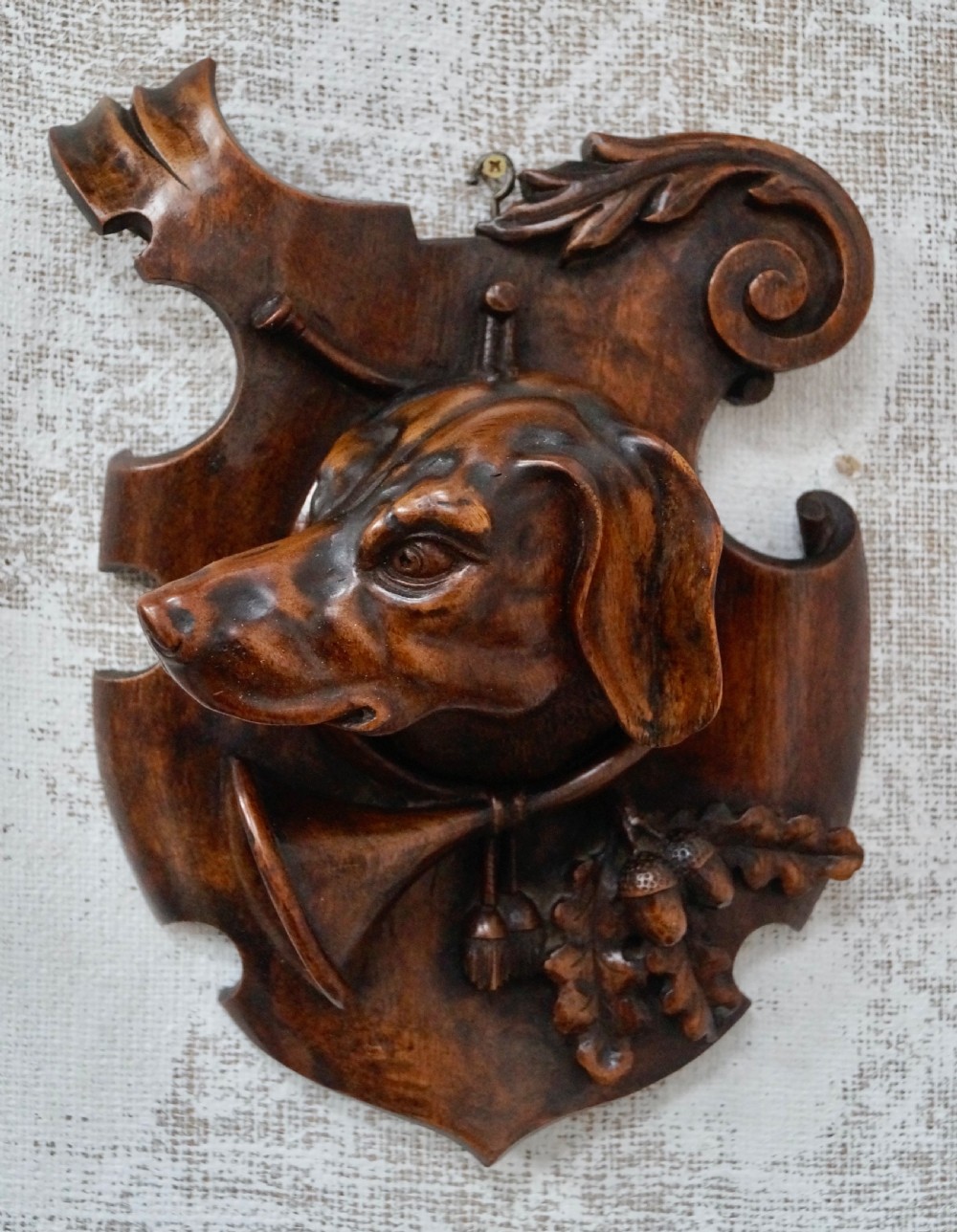 A pair of dark carved wooden shield-shaped wall plaques depicting relief heads of a fox and a hunting hound alongside sporting accessories. View VII