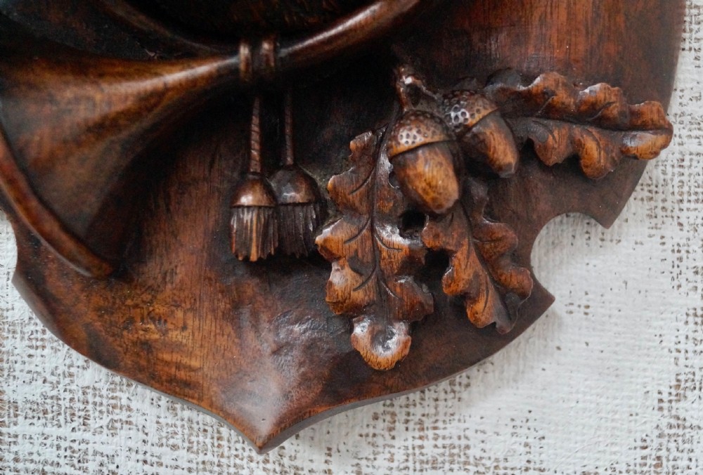 A pair of dark carved wooden shield-shaped wall plaques depicting relief heads of a fox and a hunting hound alongside sporting accessories. View VIII