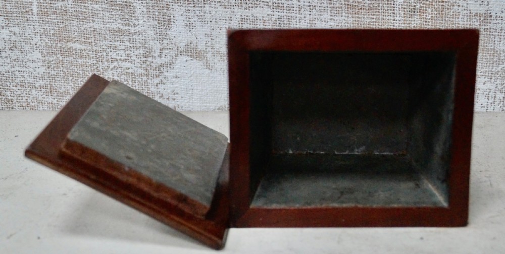 A mahogany sarcophagus-shaped tea caddy featuring flared sides, a stepped hinged lid with a central brass finial, and small brass feet. View IV