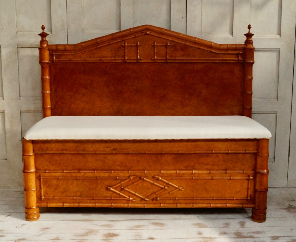An antique faux bamboo hall bench featuring turned timber frame detailing, a shaped backrest with geometric cresting, and an off-white upholstered seat.