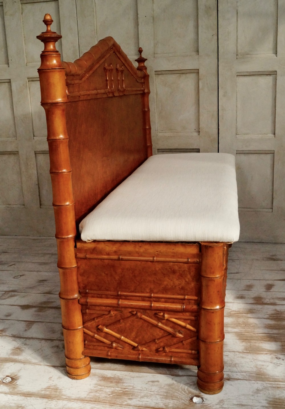 An antique faux bamboo hall bench featuring turned timber frame detailing, a shaped backrest with geometric cresting, and an off-white upholstered seat. View VIII