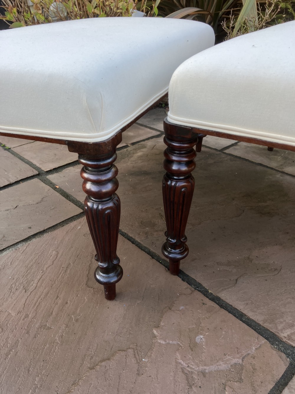 A pair of Victorian mahogany footstools with off-white upholstered rectangular tops and turned fluted legs. View III