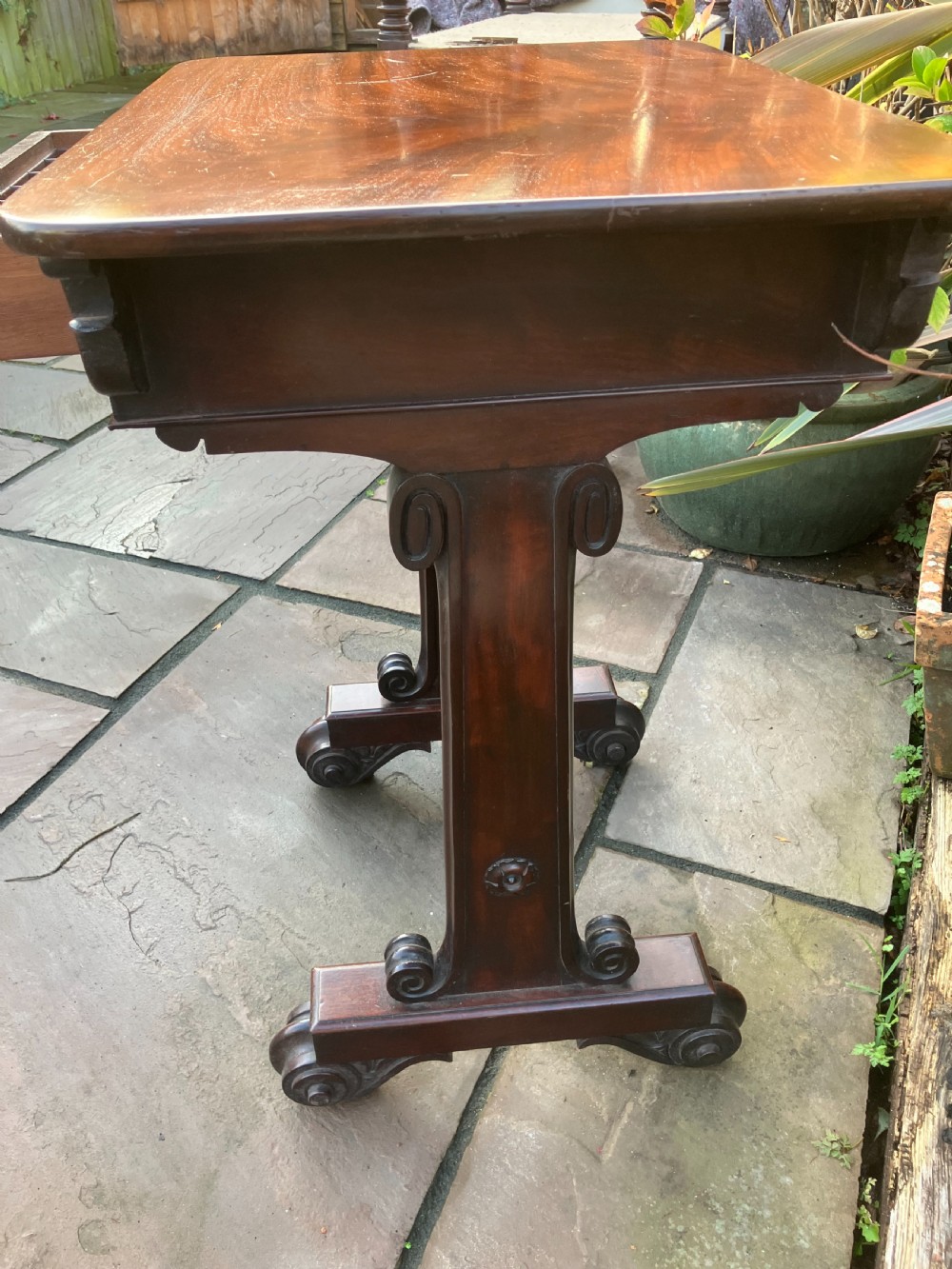 A William IV mahogany side table featuring a single drawer with turned knobs, resting on turned trestle supports and scroll feet. View III