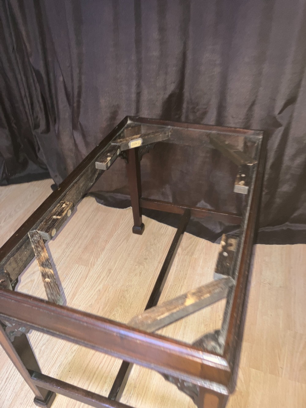 An Edwardian mahogany rectangular stool with light wood inlay on tapered legs, corner fretwork spandrels, an H-stretcher, and a green upholstered seat. View IV