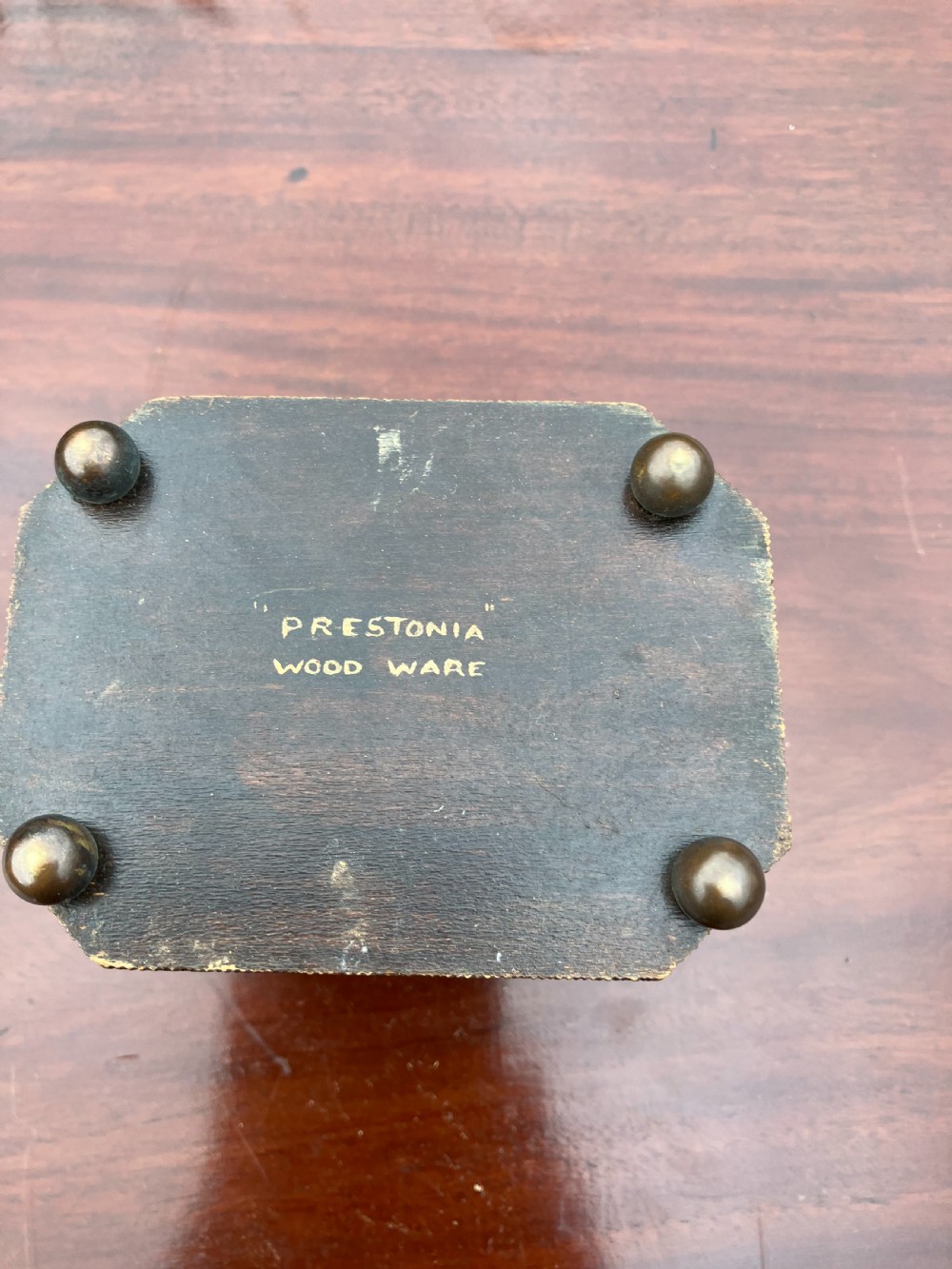 An octagonal wooden tea caddy featuring a textured stippled dark brown body, small brass feet, and painted yellow and red floral designs on the lid and front panel. View IV