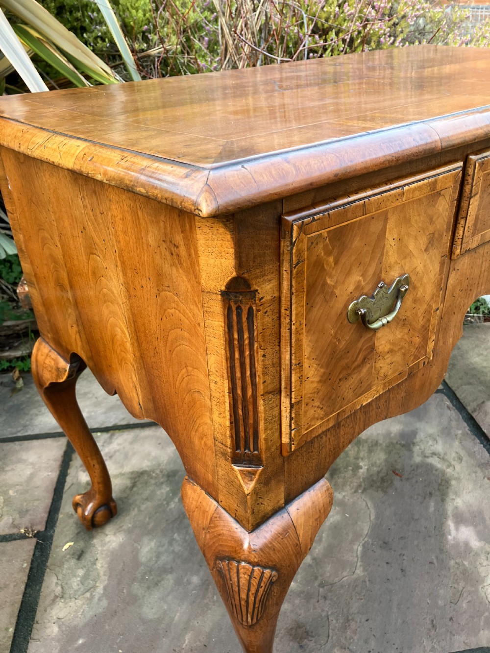 A Queen Anne style walnut lowboy featuring three drawers, brass drop handles, a shaped apron, and cabriole legs ending in ball and claw feet. View III