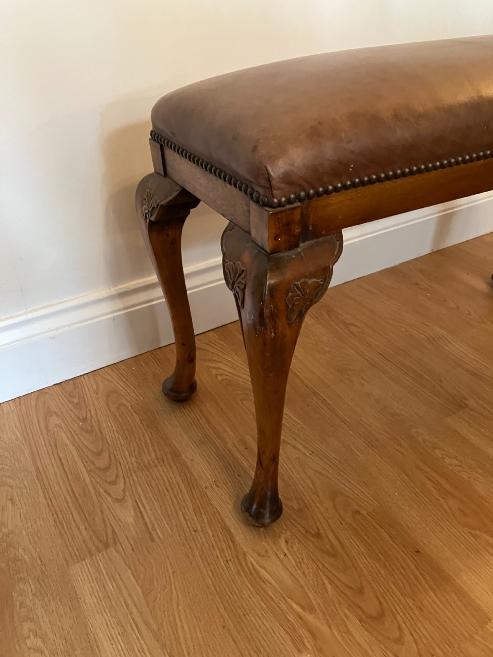 An Edwardian rectangular piano stool featuring brown leather upholstery with stud trimming and timber cabriole legs. View II