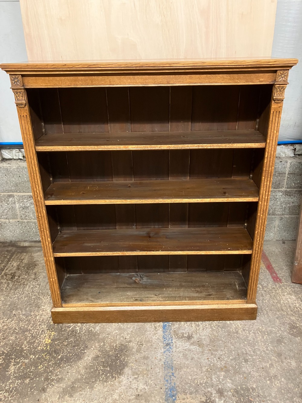 An antique Victorian oak open bookcase featuring four shelf levels, fluted pilasters, and carved corner rosettes.
