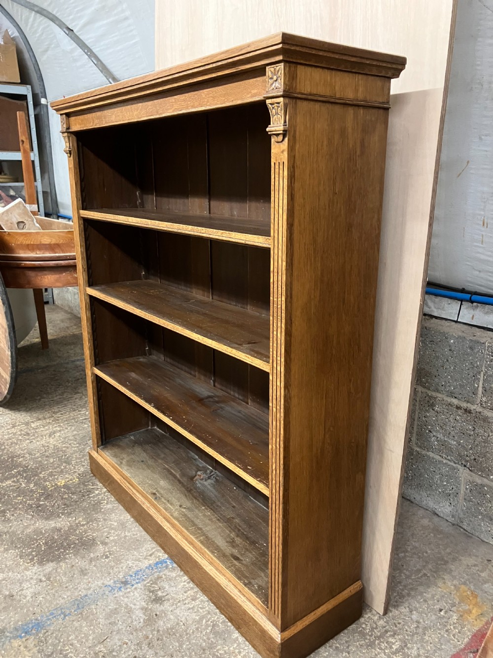 An antique Victorian oak open bookcase featuring four shelf levels, fluted pilasters, and carved corner rosettes. View V