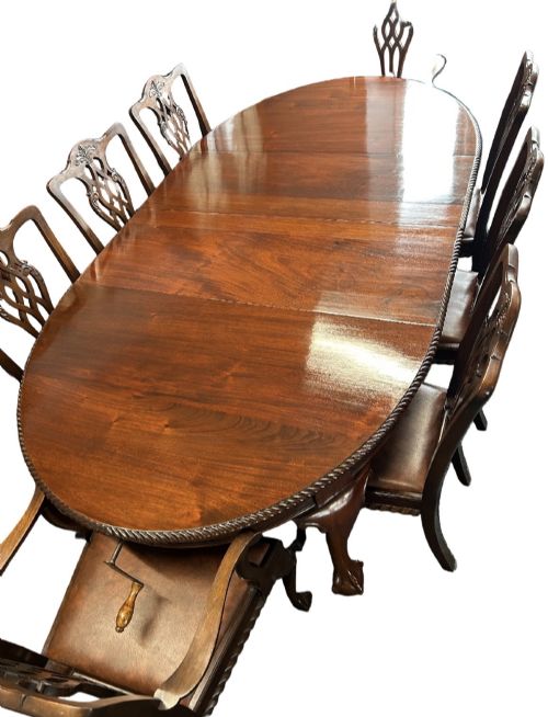 fig 1. An extending mahogany dining table featuring a carved rope edge and cabriole legs, surrounded by eight Chippendale style chairs with pierced back splats.