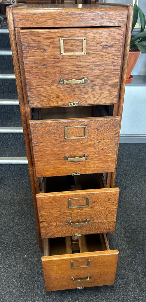 A vertical four-drawer golden oak filing cabinet featuring brass label holders and metal pull handles. View VIII