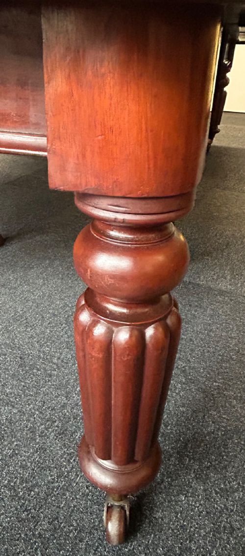 fig 1. A Victorian mahogany extending dining table featuring three insertion leaves, rounded corners, polished finish, and reeded turned legs on brass castors.
