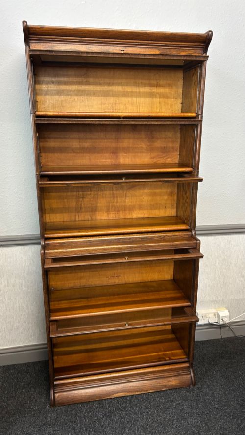 fig 2. A five-tier oak barrister bookcase with glazed up-and-over doors and small brass knobs.