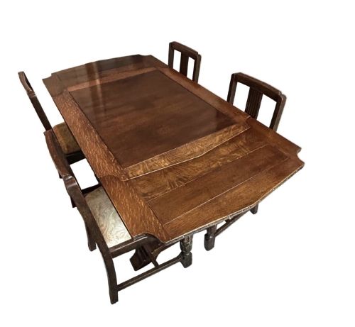 fig 1. An Art Deco dark oak dining table featuring carved legs paired with four matching chairs with patterned upholstered seats.