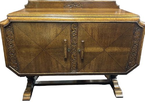 fig 1. An Art Deco dark oak sideboard featuring diamond-pattern veneered double doors, carved floral borders, wooden handles, and a low upstand gallery.