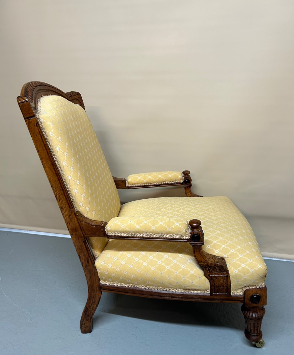 A pair of Victorian pollard oak armchairs upholstered in yellow patterned fabric featuring reeded turned legs and brass castors. View VI