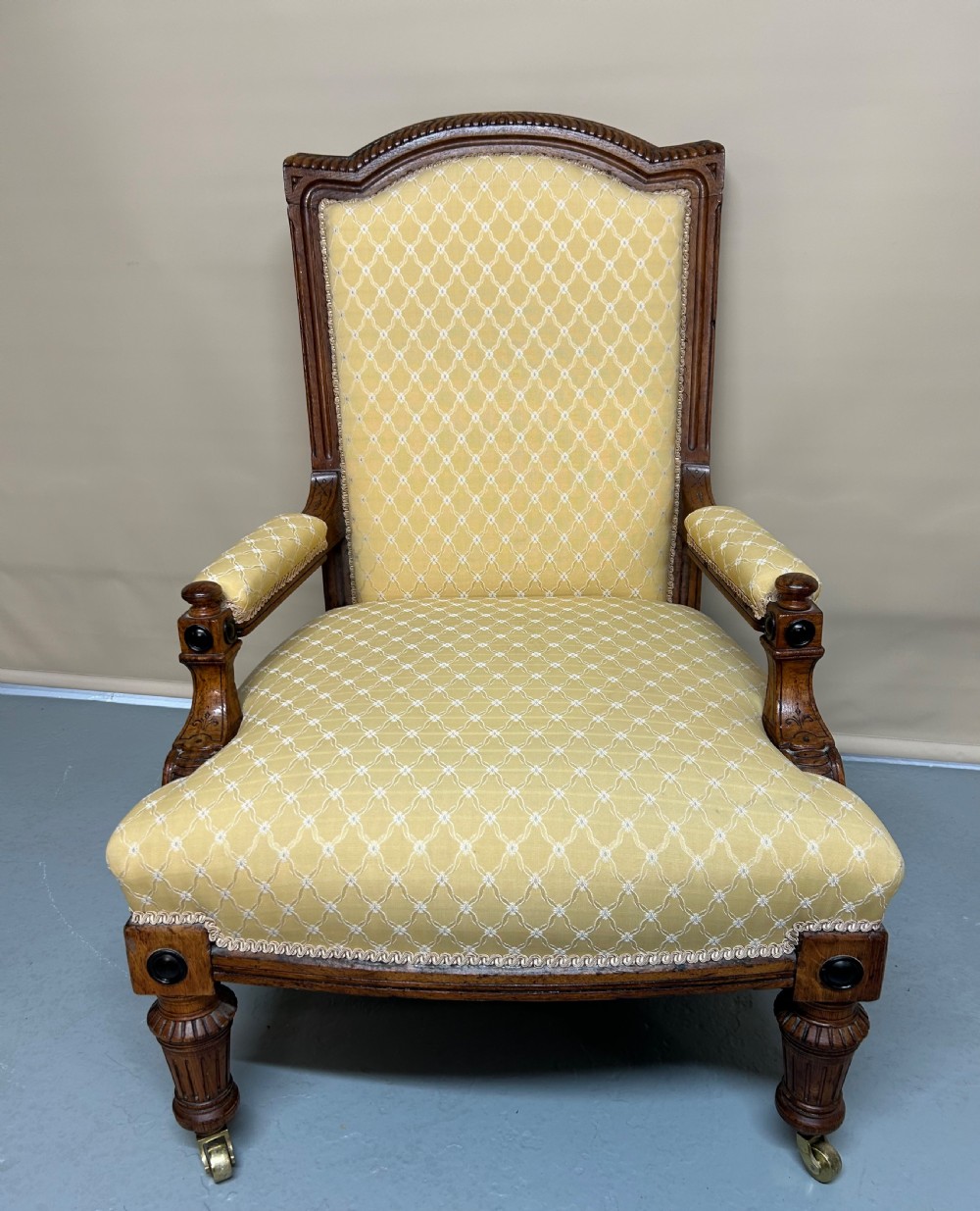 A pair of Victorian pollard oak armchairs upholstered in yellow patterned fabric featuring reeded turned legs and brass castors. View VII
