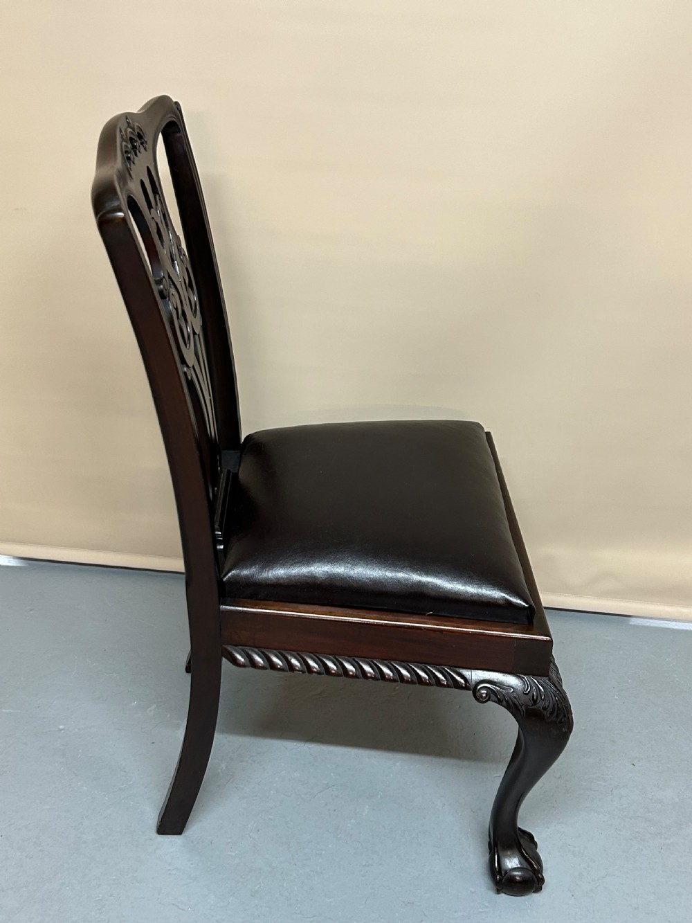 A set of six dark mahogany Chippendale style dining chairs featuring carved pierced back splats, dark leather seats, and front cabriole legs with ball and claw feet. View III
