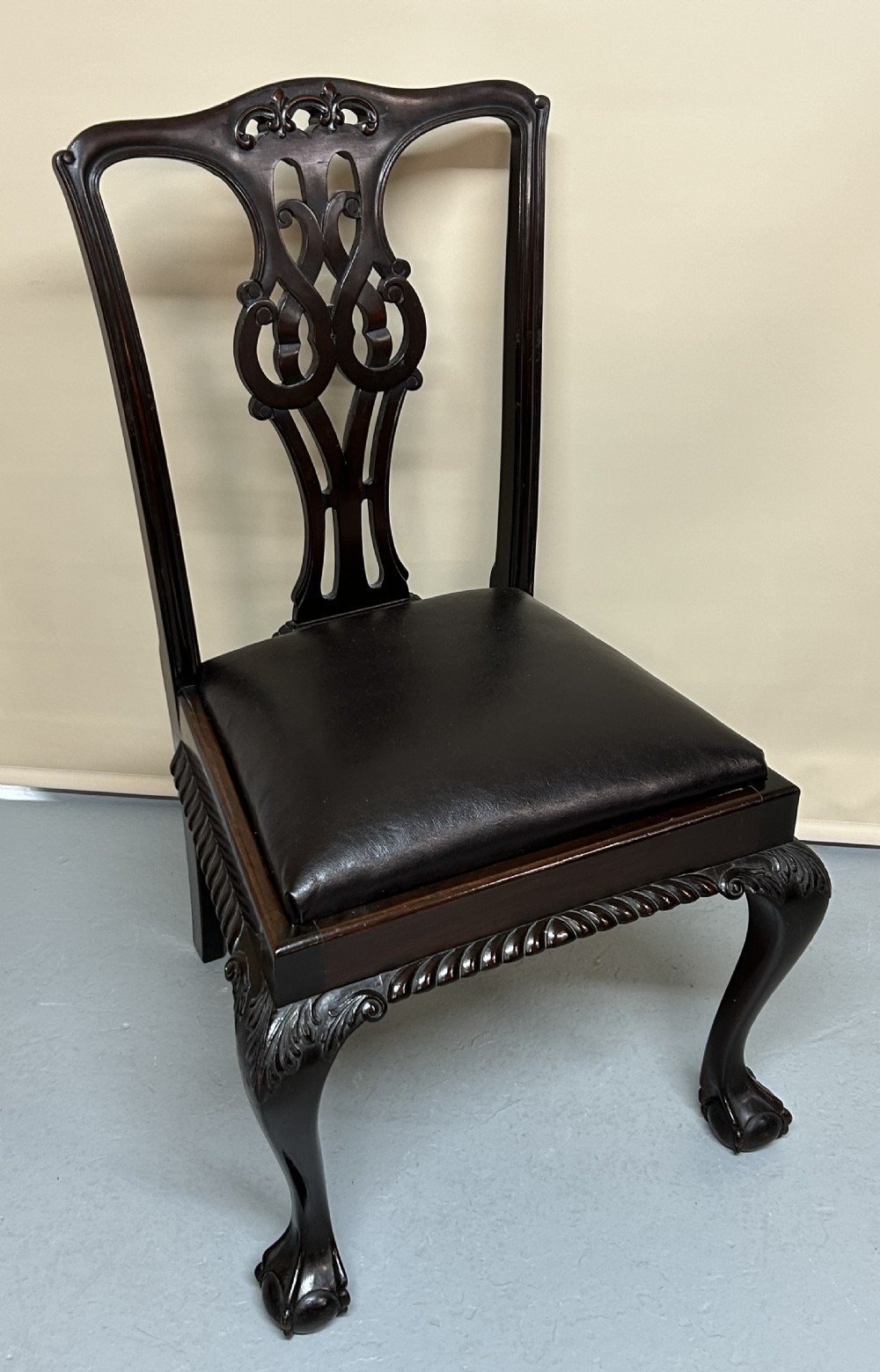 A set of six dark mahogany Chippendale style dining chairs featuring carved pierced back splats, dark leather seats, and front cabriole legs with ball and claw feet. View IV